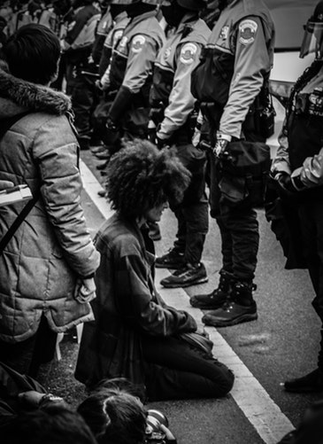 A photo of a woman kneeling in front of a group of policemen